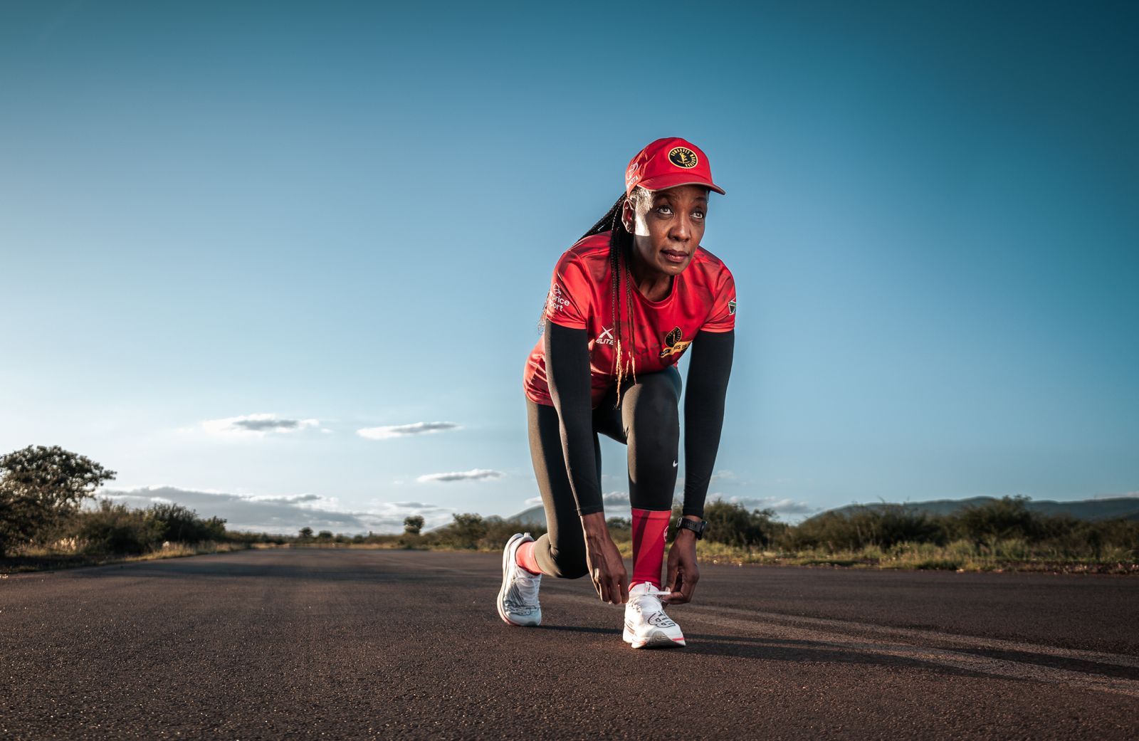 A runner preparing on an open road beneath a clear blue sky